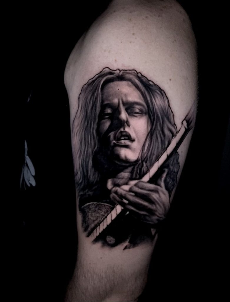 Capturing the soul of music in ink. This tattoo features a man with his guitar, embodying the passion and rhythm of a melody
